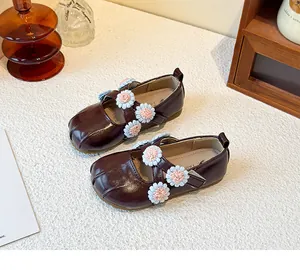 Close-up detail of dark burgundy girls Mary Jane shoes featuring fabric flower decorations