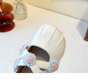 Close-up of girl's cream Mary Jane shoe featuring 3D blue and pink fabric flowers