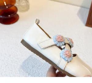 Close-up of white Mary Jane shoes with blue and pink fabric flower decorations