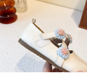 Close-up detail of girls' white Mary Jane shoes with blue and pink floral strap accents