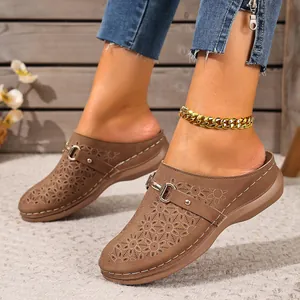 Close-up of brown women's mule sandals with floral hollow-out pattern and buckle