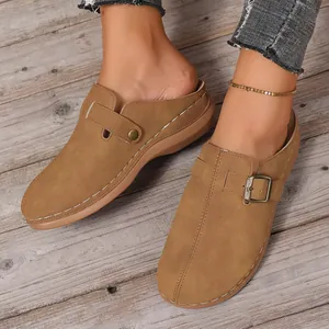 Detailed view of womens tan suede mule clogs with buckle and white stitching