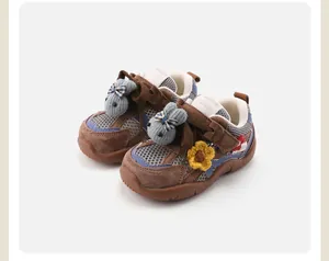 Detail view of baby shoes with plush rabbit and flower decorations on mesh upper.
