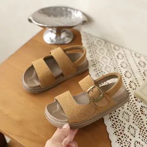 Vista dettagliata dei sandali in pelle scamosciata marrone per bambini con ricamo.