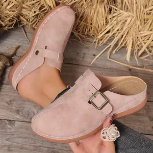 Detailed macro shot of pink suede-like mules featuring buckle and white stitching detail