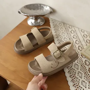 Primo piano di sandali beige per bambini con ricamo smiley e cinturino in velcro