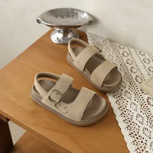Dettaglio di sandali per bambini in pelle scamosciata beige con ricamo a faccina