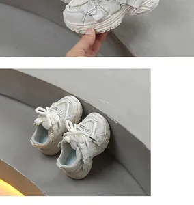 Vista detallada de zapatillas blancas de malla para niños con lazos en escalones grises