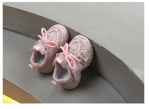 Detalle de zapatillas de malla rosa transpirable para niños con lazo decorativo