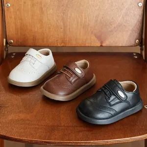 Detailed view of girls' leather shoes in white, brown, and black with brogue patterns.