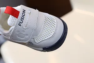 Close-up of breathable mesh toe and velcro strap on white toddler walking shoes