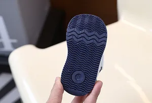 Close-up detail of the anti-slip navy blue rubber sole on a soft baby walking shoe
