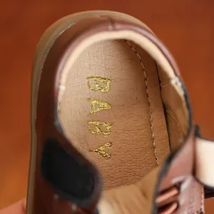 Detailed macro view of a brown girl's leather shoe interior with gold BABY lettering