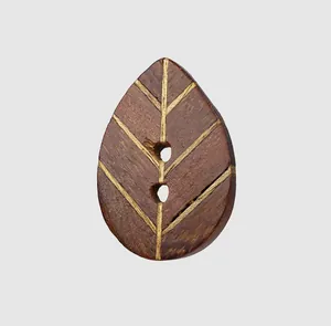 Macro detail of a teardrop-shaped ebony wood button with engraved leaf vein patterns.