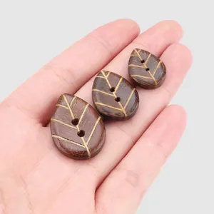 High-quality leaf-shaped ebony wood buttons for clothing held in hand for scale