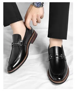 Detail view of men's black business casual leather loafers with metal buckle on white background
