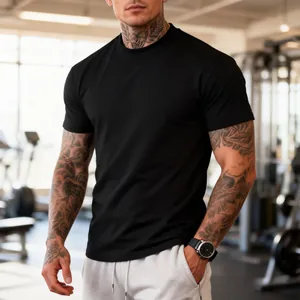 Close-up of athletic fit black crewneck t-shirt on a tattooed man in a professional gym.