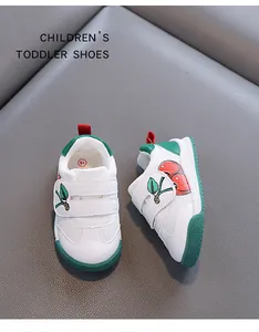 Detailed view of toddler shoes featuring white leather and green cherry design