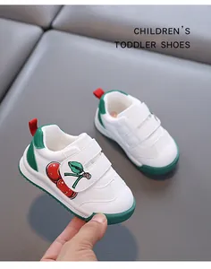 Detailed view of white toddler walking shoes with cherry embroidery and green accents