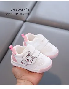 Close-up of white toddler shoes with pink accents and a cute cartoon rabbit detail.