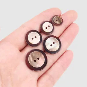 Botones de concha japonesa de alta gama en varios tamaños mostrados sobre una palma.