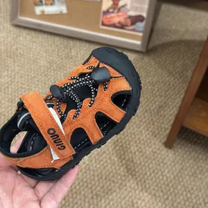 Dettaglio del sandalo sportivo arancione per bambini con cinturino e logo GINUO