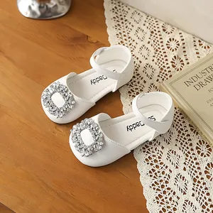 Close-up detail of white girls' Mary Jane shoes featuring a sparkling rhinestone buckle