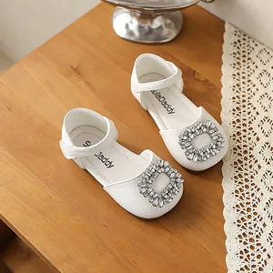 Detailed view of white girls' princess shoes featuring a sparkling rhinestone buckle.