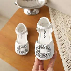 Close-up of white girls' Mary Jane shoes with sparkling rhinestone square buckle