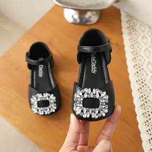 Close-up of a black girls princess shoe with a sparkling rhinestone buckle detail