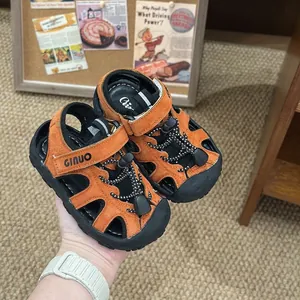 Primo piano di sandali da trekking traspiranti per bambini arancioni e neri con velcro