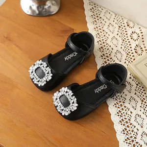 Close-up view of girls black leather shoes with sparkling rhinestone buckle details