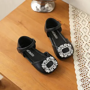 Close-up of girls black leather princess shoes with sparkly rhinestone buckle detail