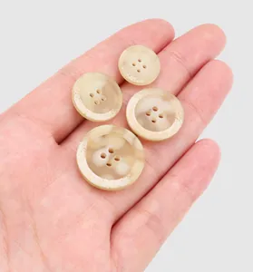 Gedetailleerd overzicht van vier gemarmerde beige harsknopen op een handpalm voor maat.