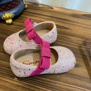 Detailed macro view of shimmering pink glitter flats for girls featuring a bright pink bow