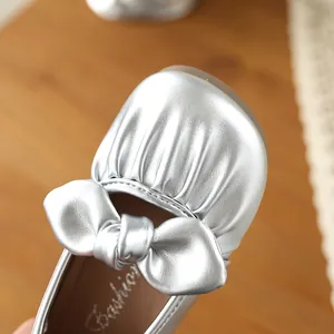 Gros plan détaillé d'une chaussure Mary Jane argentée pour fille avec nœud plissé