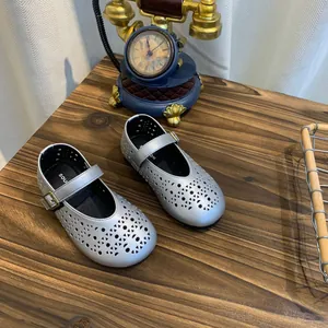 Chaussures Mary Jane argentées ajourées avec design respirant sur table en bois