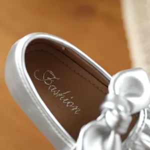 Détail en gros plan d'une chaussure Mary Jane argentée pour fille avec un nœud