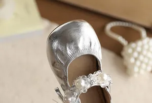 Gedetailleerde close-up van zilveren prinsessenschoenen voor meisjes met parel- en bloemenbandje