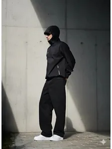 Détail d'un homme portant un jean noir oversize à coupe droite dans un décor urbain