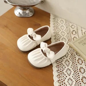 Gros plan sur les chaussures Mary Jane crème pour filles avec nœud et plis élégants