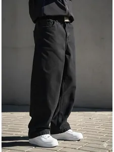 Gros plan d'un jean noir oversize en coupe droite décontractée pour hommes urbain.