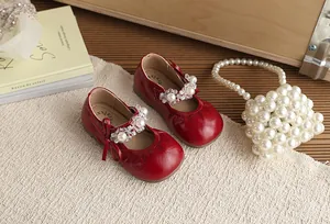 Close-up van elegante rode prinsessenschoenen voor meisjes met parels en strikdetails