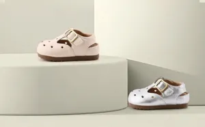 Detailed view of baby leather sandals in cream and silver with buckle straps