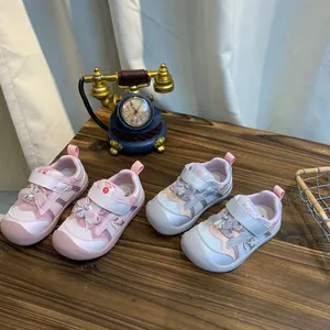 Detailweergave van twee paar schattige kindersneakers met strikjes op een houten tafel