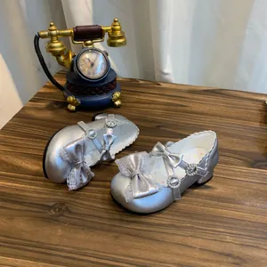 Detalle de zapatos de princesa plateados para niñas con lazo y perlas