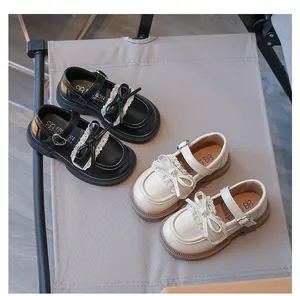 Detailansicht von schwarzen und cremefarbenen Mädchenschuhen mit Spitzen-Schleifendekor