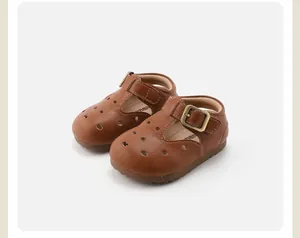 Close-up of brown leather T-strap baby shoes with hollow-out design and soft sole