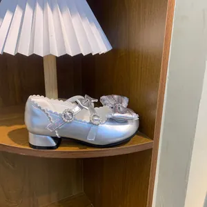 Vista detallada de zapatos de princesa Lolita plateados con lazo y perlas en un estante de madera