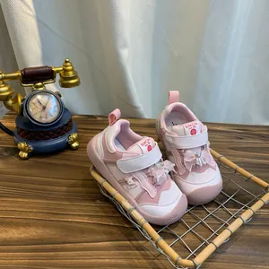Close-up van roze kindersneakers met schattige decoratieve strikken en klittenbandsluiting